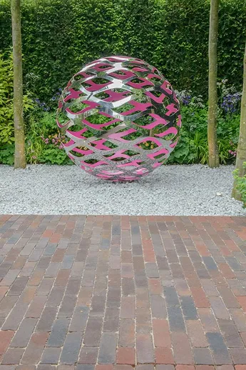 Pierced ball sculpture on white gravel, with Abbey Dark Multi brick pavers on RHS Chelsea trade stand. Design by Nic Howard.