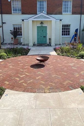 Firepit in centre of large circle of Old English Dutch Clay Paving in front of Neo-Georgian house. Built by AJT Landscaping.