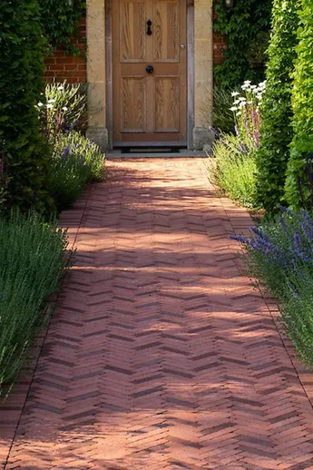 Path of Spalding Brick Pavers laid herringbone with soldier course edges runs between beds to front door. Design by Ana Mari Bull.