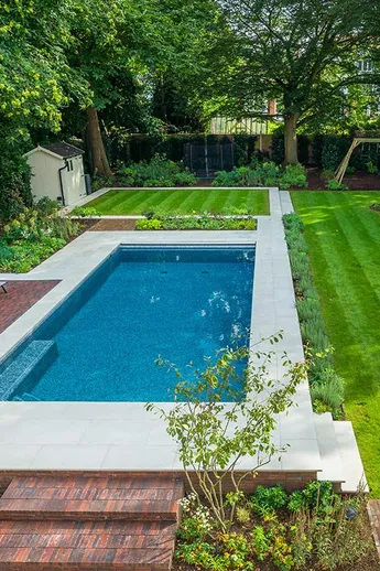 Swimming pool in garden with mature trees and lawns. Pool surround and paths of Antique Red Clay Pavers and sawn sandstone paving.