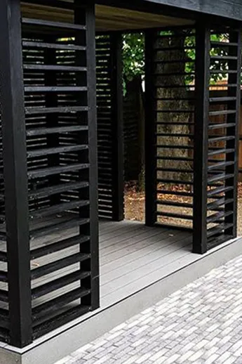 Apron of Silver Grey Multi Clay Pavers fronts Japanese-style black wood pergola on decking plinth in garden by Landmark Landscapes.