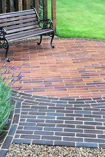 A bench on paving circle of Bromley Belgian Bricks edged and approached by Lugano clay pavers. Design by Outsiders Landscaping.